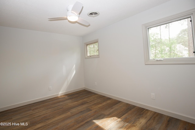 empty room featuring a ceiling fan, baseboards, visible vents, and dark wood finished floors
