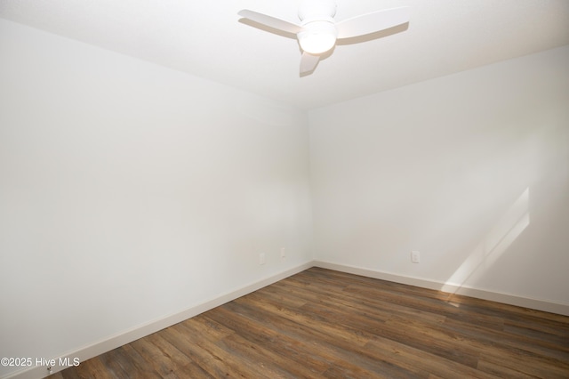 spare room with baseboards, a ceiling fan, and dark wood-style floors