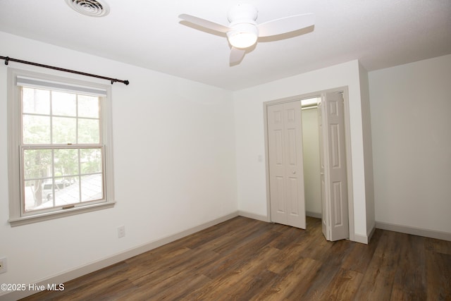 unfurnished bedroom with visible vents, baseboards, dark wood-style floors, and a closet