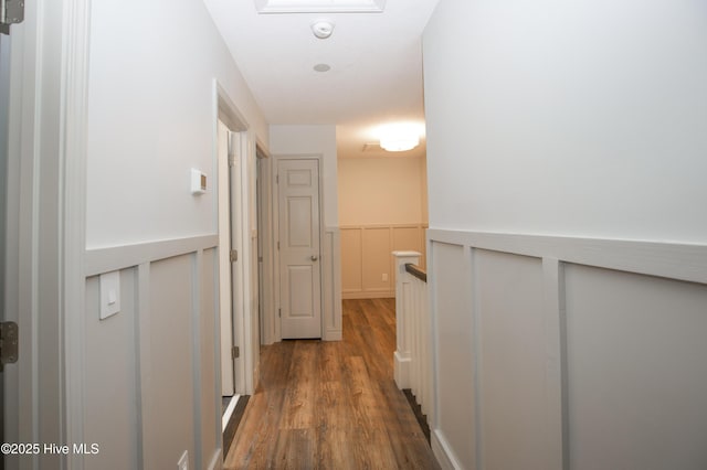 hall featuring dark wood-style flooring and a wainscoted wall