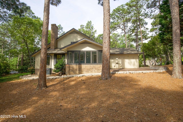 view of front of property with brick siding, central AC, and a chimney