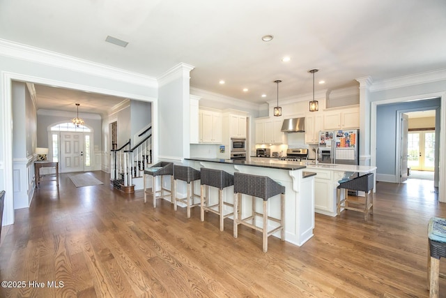 kitchen featuring crown molding, extractor fan, appliances with stainless steel finishes, and a breakfast bar