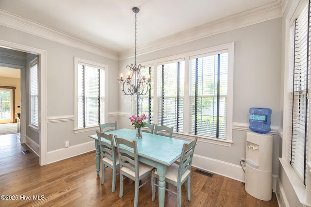dining space featuring visible vents, ornamental molding, wood finished floors, and an inviting chandelier