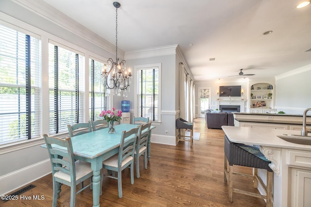 dining space featuring baseboards, ceiling fan with notable chandelier, a healthy amount of sunlight, and a fireplace