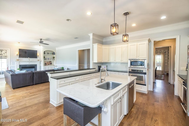kitchen featuring plenty of natural light, a ceiling fan, appliances with stainless steel finishes, a sink, and ornamental molding