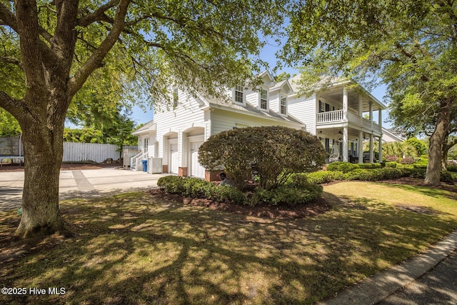 view of side of property with concrete driveway, fence, a balcony, and a garage