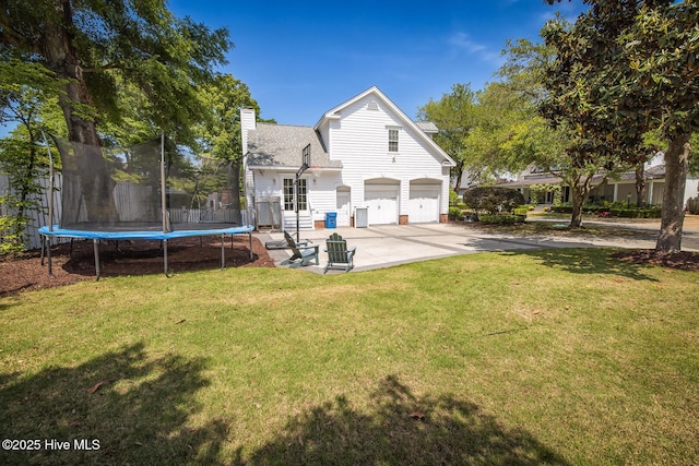view of front of property with roof with shingles, a trampoline, a garage, a chimney, and driveway