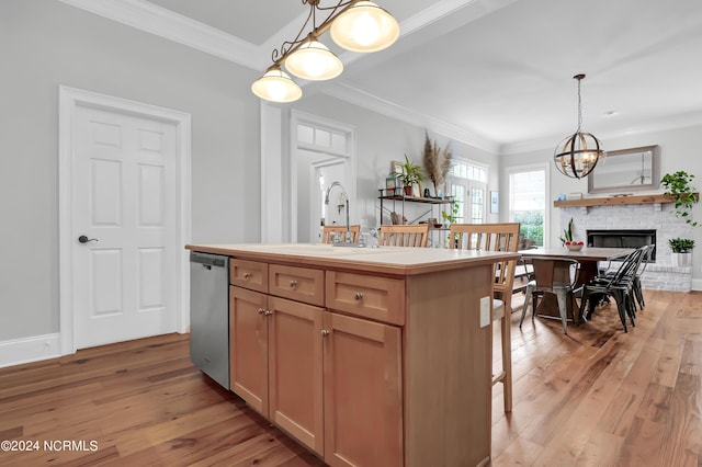 kitchen with a sink, a brick fireplace, light wood-type flooring, decorative light fixtures, and stainless steel dishwasher