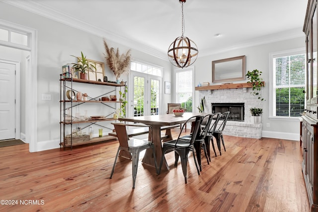 dining room with a chandelier, baseboards, crown molding, and a brick fireplace