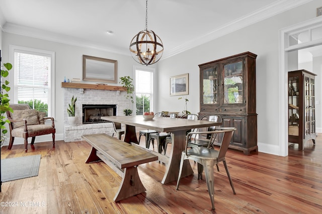 dining room featuring a brick fireplace, ornamental molding, and light wood-style flooring