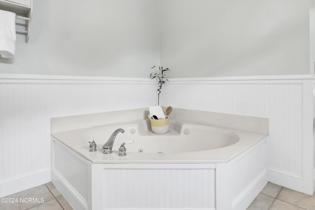bathroom with a whirlpool tub, a wainscoted wall, and tile patterned floors