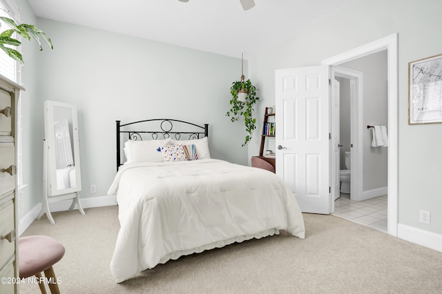 bedroom with baseboards, vaulted ceiling, light carpet, and ensuite bathroom