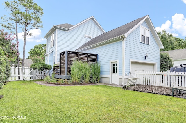 rear view of property featuring fence, a yard, and a garage