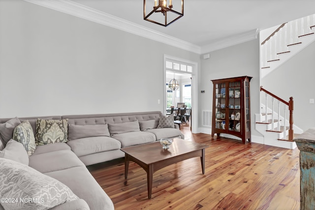living area with an inviting chandelier, light wood-type flooring, ornamental molding, and stairs