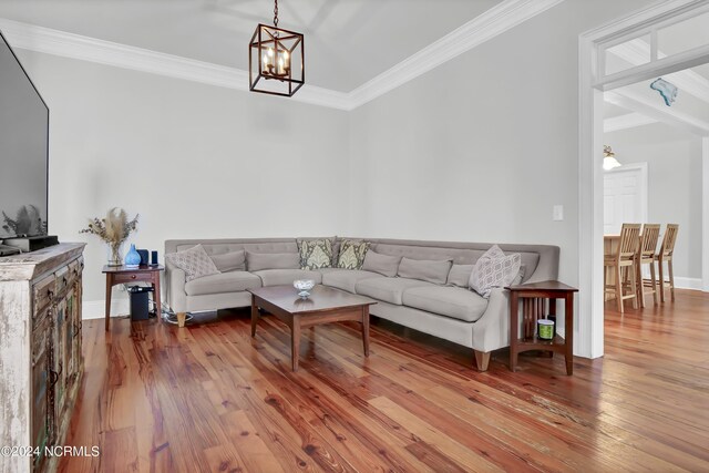 living room featuring an inviting chandelier, wood finished floors, ornamental molding, and baseboards