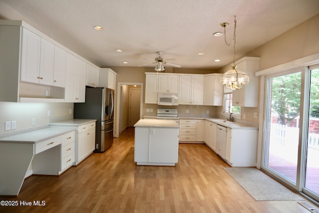21 Birdie Dr, Whispering Pines, NC 28327 - kitchen with a sink, white appliances, light wood-style flooring, ceiling fan with notable chandelier, and a center island