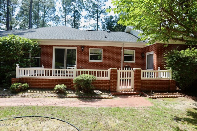 21 Birdie Dr, Whispering Pines, NC 28327 - back of property with roof with shingles, a yard, and brick siding