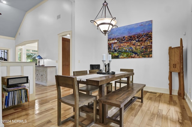 dining space with light wood-style flooring, baseboards, high vaulted ceiling, and visible vents