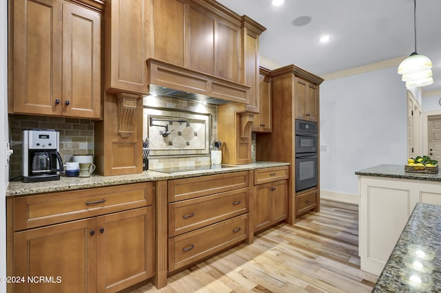 kitchen with brown cabinetry, backsplash, black appliances, and light wood-style floors