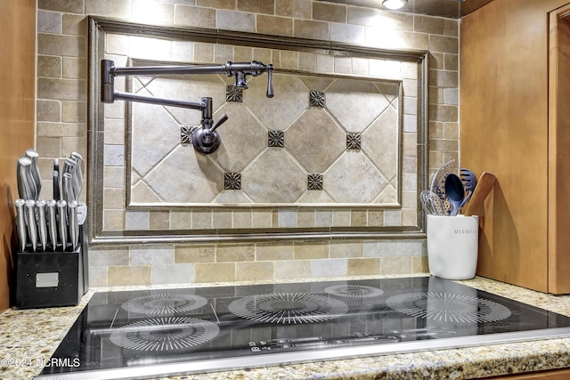 details featuring black electric cooktop and light stone counters