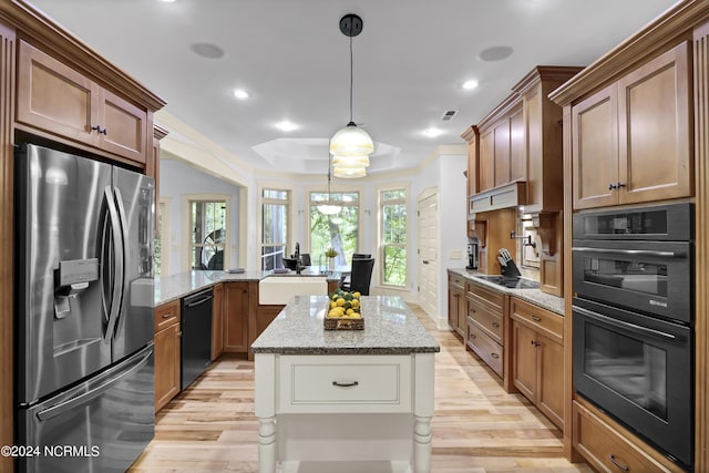 kitchen featuring black appliances, light wood finished floors, light stone countertops, and a peninsula