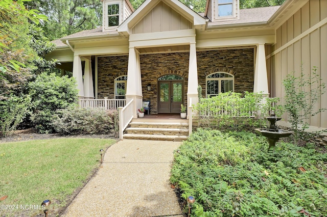 property entrance with stone siding, board and batten siding, a porch, and a shingled roof