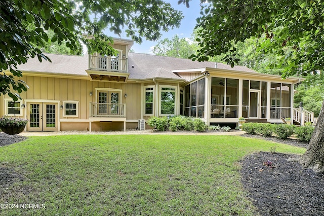 rear view of property with french doors, a sunroom, a balcony, a yard, and roof with shingles