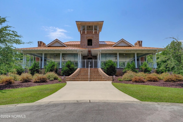 farmhouse featuring a chimney, a standing seam roof, stairway, metal roof, and a porch