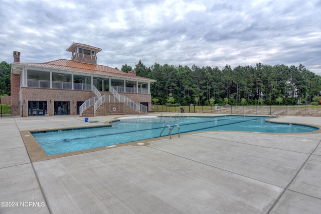 pool featuring a patio area, stairway, and fence