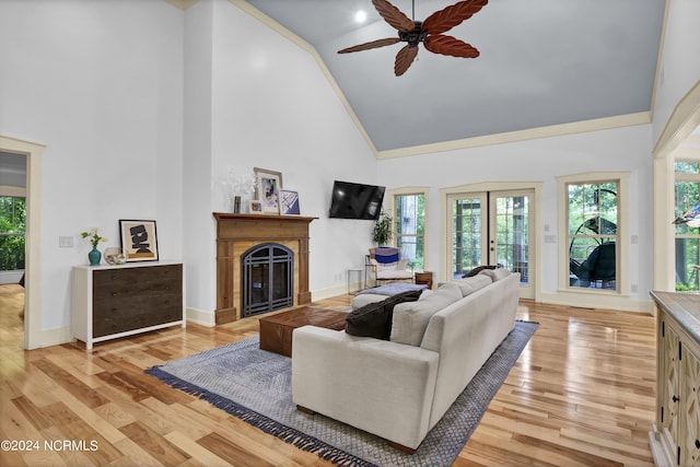 living area featuring a fireplace, ceiling fan, high vaulted ceiling, and light wood-style floors