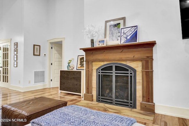 interior space featuring baseboards, a fireplace with flush hearth, visible vents, and wood finished floors