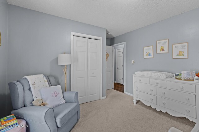 sitting room featuring carpet, a textured ceiling, and baseboards