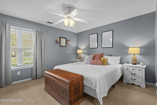 carpeted bedroom featuring a textured ceiling, visible vents, a ceiling fan, and baseboards