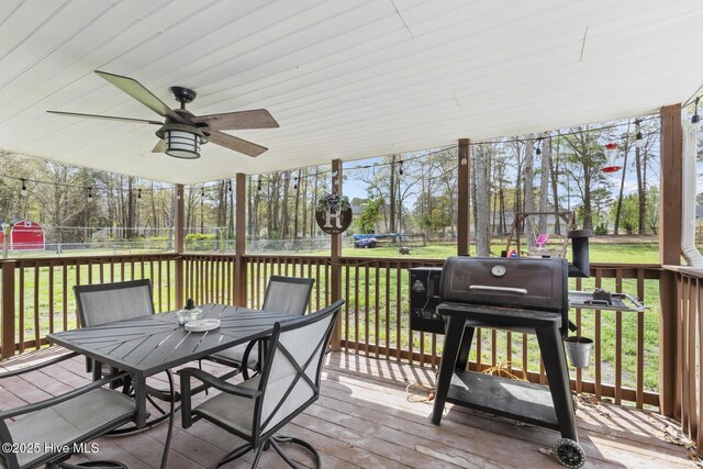 deck with a ceiling fan, outdoor dining area, and a yard