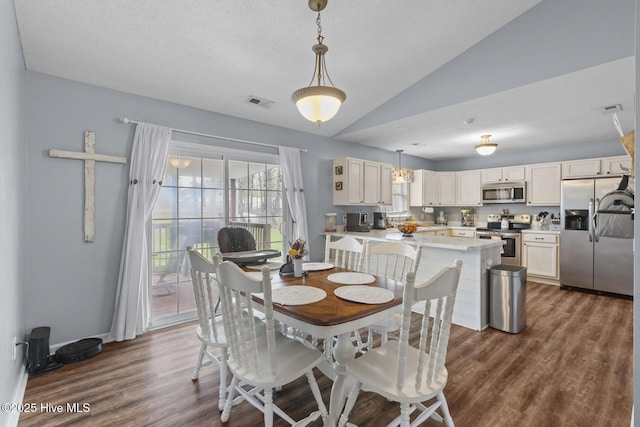 dining space featuring vaulted ceiling, dark wood-type flooring, visible vents, and a textured ceiling