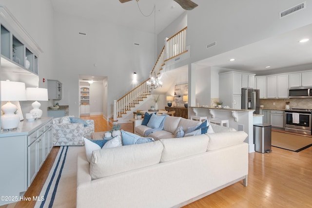 2537 St James Dr SE Apt 1011, Southport, NC 28461 - living room featuring light wood-style floors, stairway, visible vents, and a high ceiling