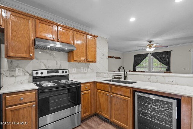 kitchen with electric stove, beverage cooler, under cabinet range hood, ornamental molding, and a sink