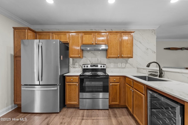 kitchen featuring a sink, under cabinet range hood, stainless steel appliances, ornamental molding, and beverage cooler