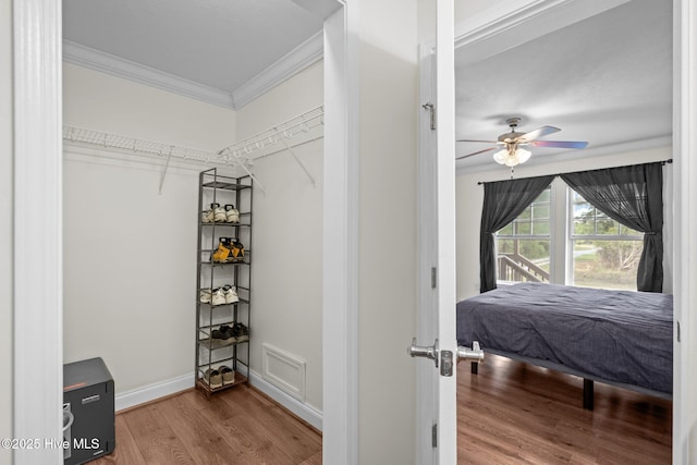 bedroom with baseboards, wood finished floors, ceiling fan, and crown molding