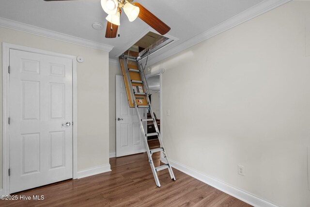 below grade area with wood finished floors, a ceiling fan, baseboards, and ornamental molding