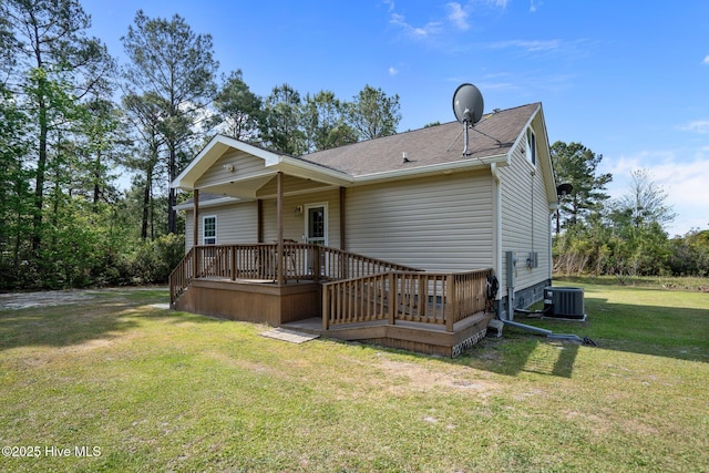exterior space featuring central air condition unit, a wooden deck, roof with shingles, and a lawn
