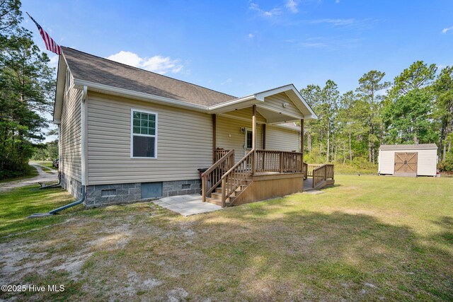 view of front of house with a shingled roof, a front lawn, an outbuilding, and a storage shed