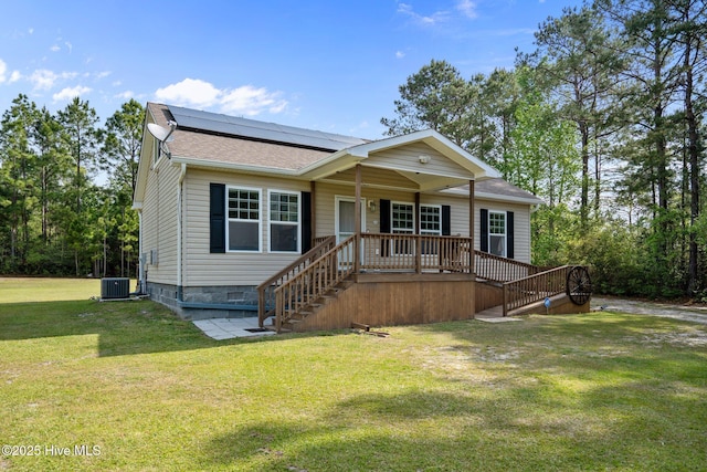 view of front of home with a front yard, stairs, solar panels, and a shingled roof