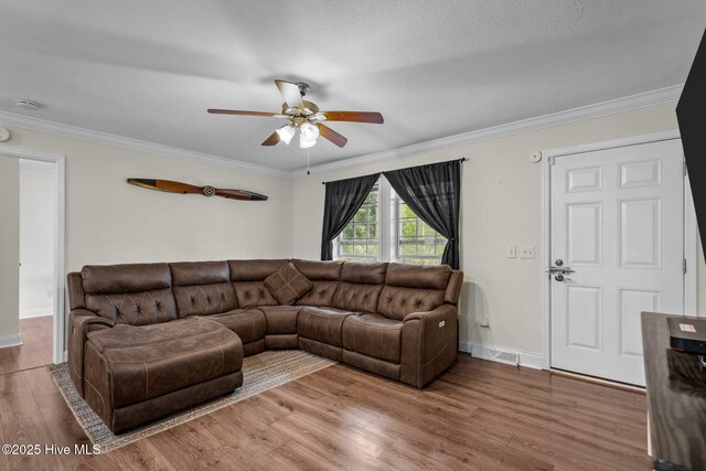 living area with ceiling fan, visible vents, baseboards, ornamental molding, and wood finished floors