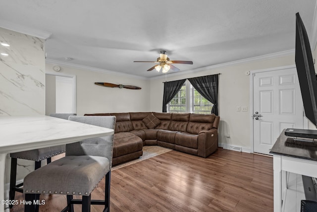 living area featuring crown molding, wood finished floors, a ceiling fan, and baseboards