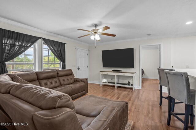 living room featuring wood finished floors, ceiling fan, crown molding, and baseboards