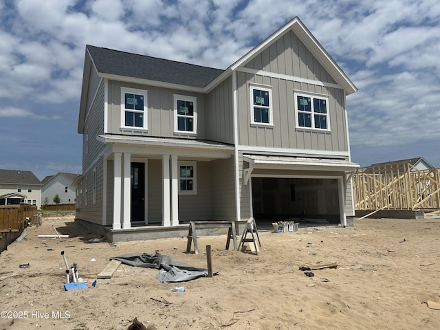 view of front facade with board and batten siding, fence, and a garage
