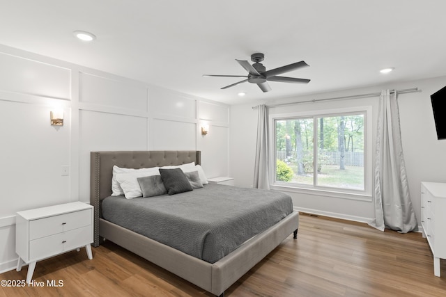 bedroom featuring recessed lighting, light wood-type flooring, and a decorative wall