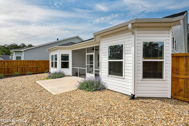 back of property with ceiling fan, a sunroom, a patio, and a fenced backyard