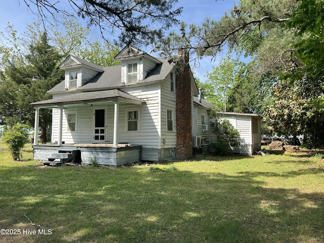 exterior space featuring a porch, roof with shingles, a chimney, and a lawn